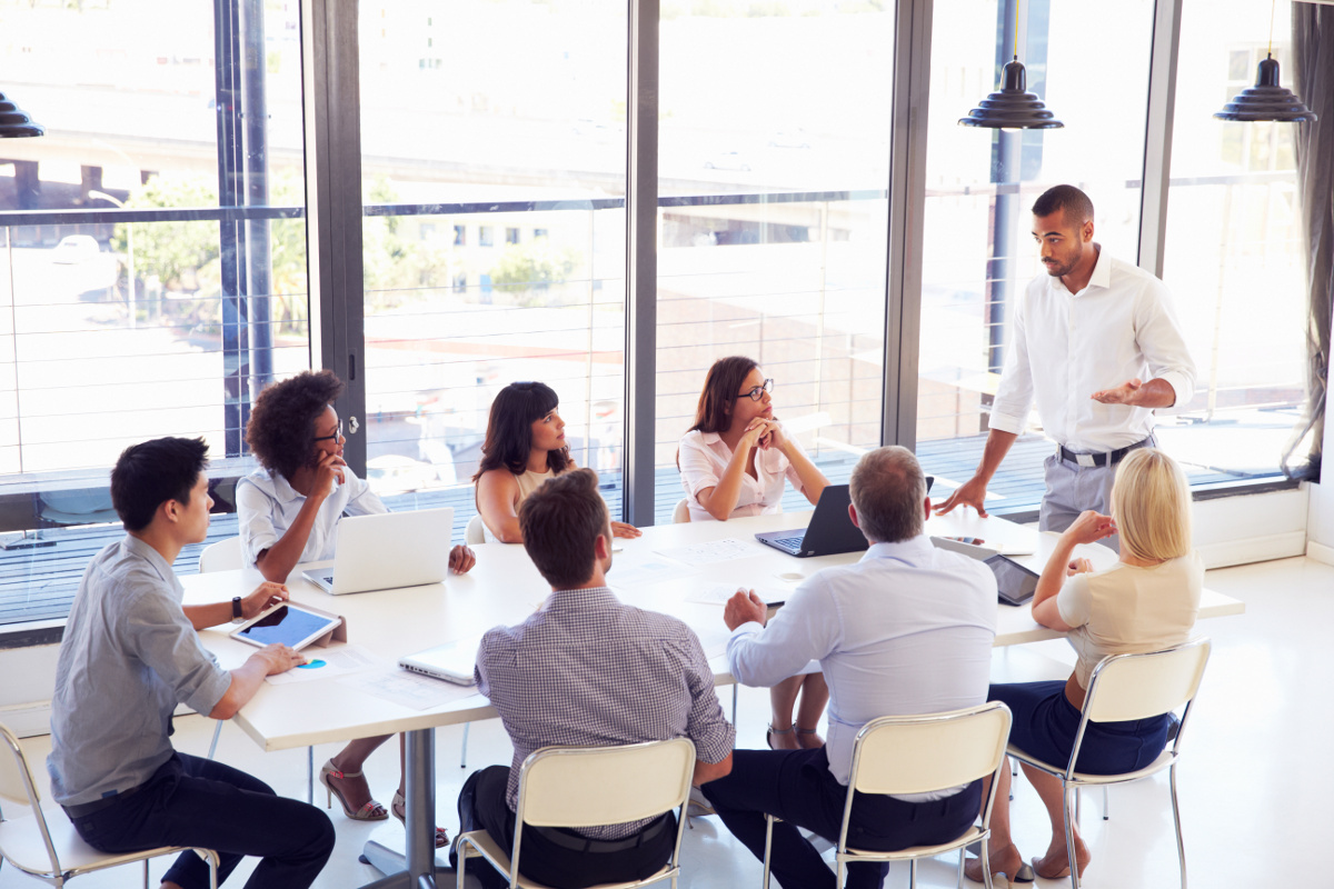 Small Business Team Around White Meeting Table in Modern Conference Room