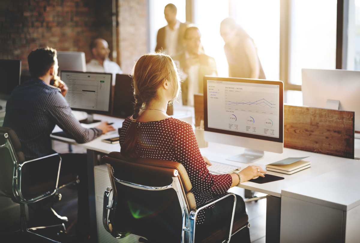 Business People Sitting at Desk Checking Email and Analytics on Computer