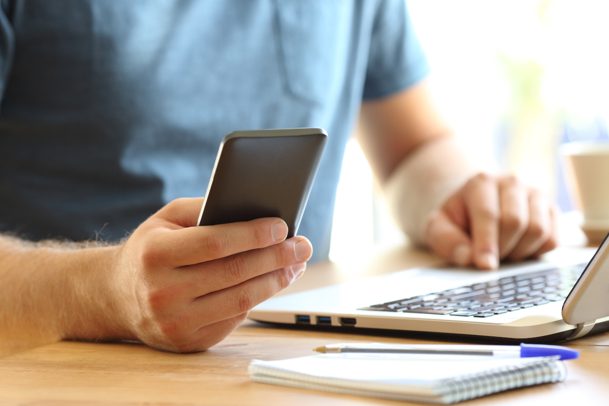 A man using his cellphone and a laptop for work