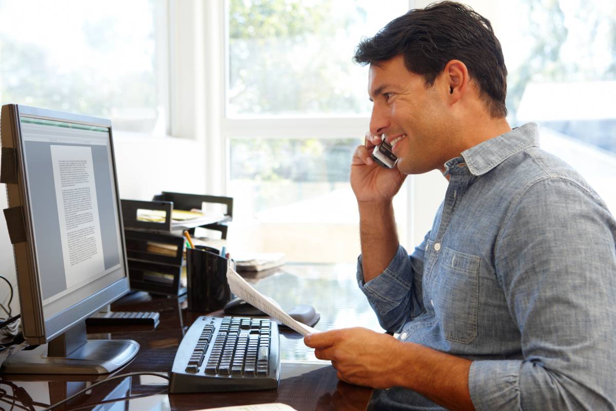 A man working from home using a laptop and a headset