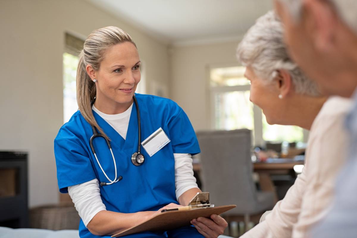 A nurse speaking with two elderly patients