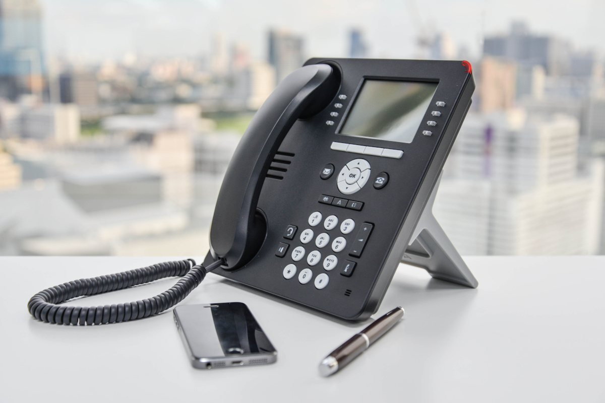 An office desk phone and a mobile phone on a desk