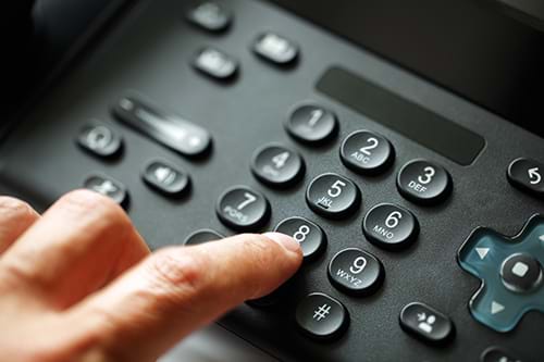 Close Up of Finger Pressing the Number 8 on VoIP Desk Phone Keypad