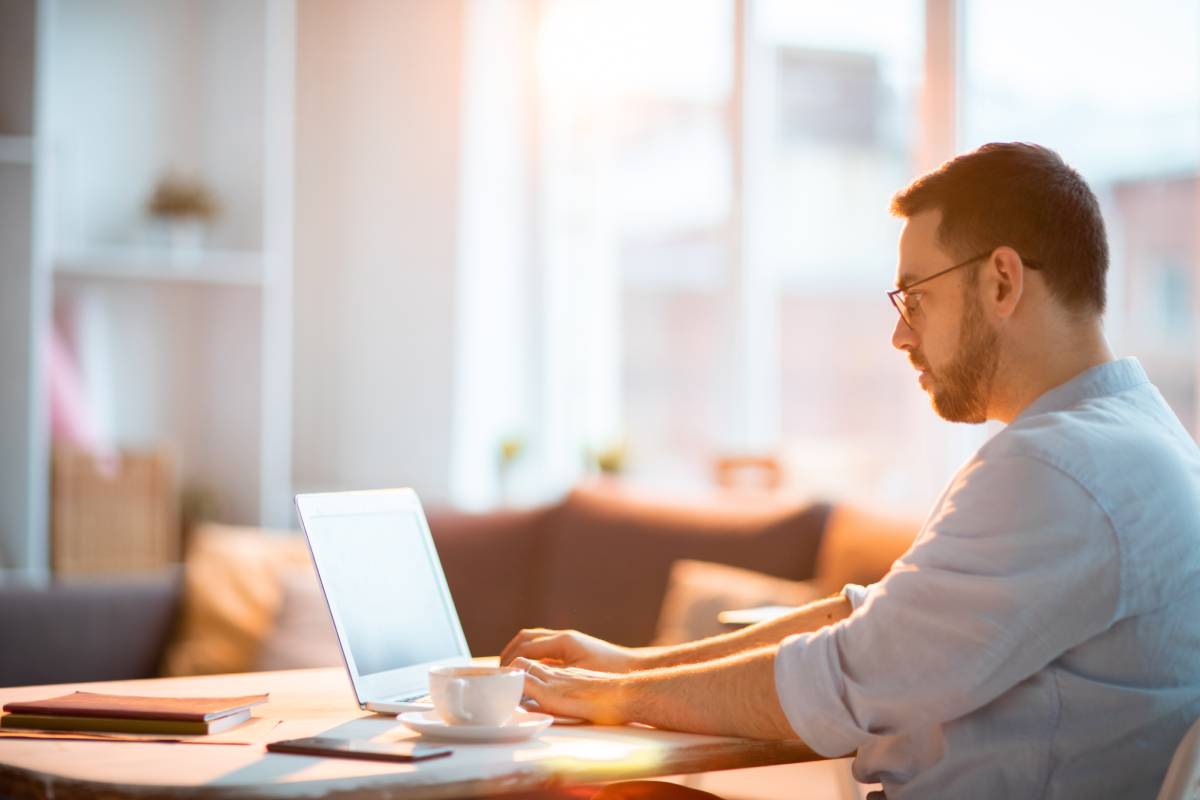 Man using laptop while mobile phone is next to him